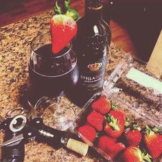 some strawberries and wine are sitting on a counter top next to a pair of scissors