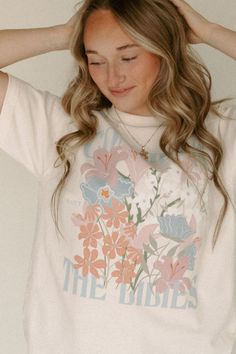 This graphic is beautifully printed from top to bottom with our freshly drawn lilies + wildflowers. These spring colors can easily be matched for styling with layers! Unisex A. Apparel Tee 100% Ring-spun Cotton. Order+ Shipping Policy: https://chaudoincreationsky.com/pages/shipping-policy Refund /Exchange Policy: https://chaudoincreationsky.com/pages/refund-policy Consider The Lilies, Wrangler Accessories, Headband Jewelry, Summer Glow, Quirky Design, Midi Maxi Dress, Flower Child, Spring Colors, Swimwear Tops