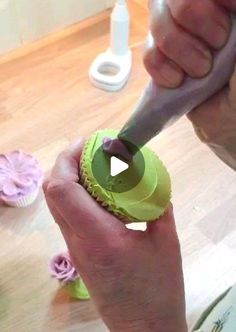 a person holding a green cupcake in their hand with a knife sticking out of it