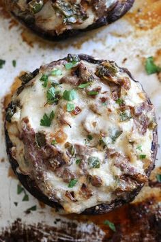 two stuffed mushrooms with cheese and green onions on a sheet of baking paper next to an instagram post