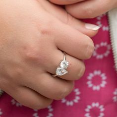 a close up of a person's hand with a ring on their finger, wearing a pink and white dress