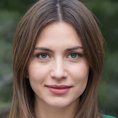 a close up of a person with long hair and blue eyes wearing a green shirt