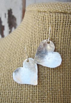 "I cut these two free form hearts from a sheet of sterling silver metal and hammered them to create these rustic earrings. They are coated to prevent tarnishing. The hearts have a slight curve to them to pick up shine from the hammered indensions. They measure 1 1/4\" in length from the top of the sterling silver earwire. Very lightweight and comfortable for all day wear. See the longer heart version here: https://www.etsy.com/listing/129416439/valentines-gift-sterling-silver-heart?ref=shop_home Metal Sheet Jewelry, Hammered Silver Heart Jewelry, Heart-shaped Hammered Sterling Silver Jewelry, Sterling Silver Earrings For Mother's Day Anniversary, Sterling Silver Earrings For Anniversary, Sterling Silver Earrings For Anniversary And Mother's Day, Silver Heart Earrings For Anniversary On Valentine's Day, Sterling Silver Earrings For Anniversary Gift, Silver Sterling Silver Earrings For Anniversary Gift