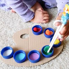 a toddler is playing with paints on the floor