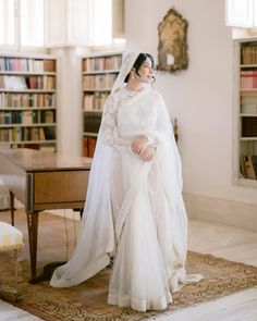 a woman in a white wedding dress standing next to a table with books on it