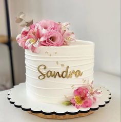 there is a white cake with pink flowers on the top and gold lettering that says sandara