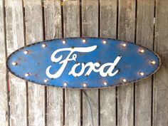 a blue sign that says ford on the side of a wooden fence with string lights