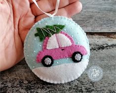 a hand holding a small ornament with a pink car on it's side