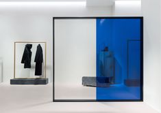 an empty room with blue and white walls, clothes hanging on the wall, and a mirror