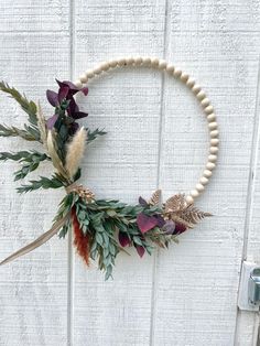 a wreath made out of flowers and leaves is hanging on a white wooden door frame