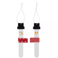 two snowmen made out of popsticks are hanging from strings