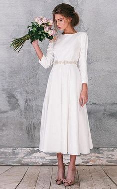 a woman in a white dress holding flowers