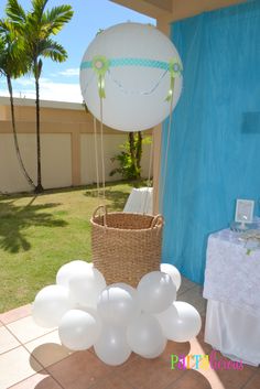 a table topped with white balloons next to a blue wall and green grass covered yard