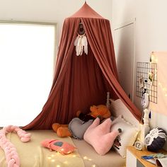 a bed with a canopy over it and stuffed animals on the floor next to it