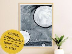 a white vase sitting on top of a wooden table next to a framed art piece