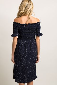 a woman wearing a black polka dot dress with off the shoulder sleeves and ruffles