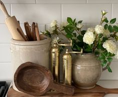 kitchen utensils and wooden spoons sit on a cutting board next to flowers