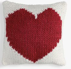 a red and white knitted heart pillow