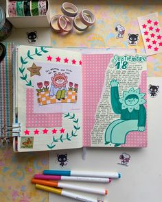 an open notebook with various stickers and scissors on it, next to some crafting supplies