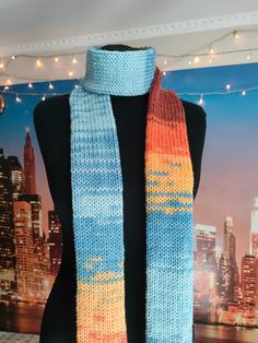 a blue and orange knitted scarf hanging from a mannequin