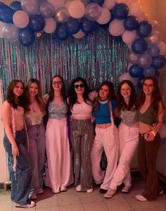 a group of women standing next to each other in front of balloons and streamers