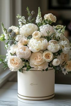 a bouquet of white flowers sitting on top of a table next to an open window