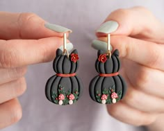 a pair of black cat shaped earrings with red flowers on the front and back of them