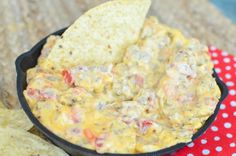 tortilla chips and dip in a black bowl on a red polka dot tablecloth