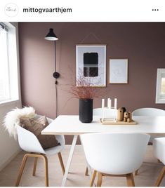 a dining room table with white chairs and a black vase on it's side