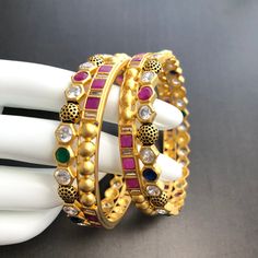 Navratan bangles/ Bridal Kundan Meenakari bangles/ 2.4,2.6 Ruby Kundan Bangles/ Indian Bollywood Wedding Bangles/ Golden Indian Bangles Features Traditional Kundan/Polki/Meenakari bangles Set Handcrafted To Perfection Light Weight Bangles Perfect For Indian Weddings And Celebrations A Beautiful & Memorable Gift for Weddings and Special Occasions Available in 2.4, 2.6 size The base metal color is Gold tone brass studded with colorful semi-precious Navratan stones on it. Facebook: www.facebook Multicolor Round Chandbalis With Intricate Design, Multicolor Temple Jewelry Bangle For Festive Occasions, Multicolor Chandbalis With Intricate Design, Multicolor Chandbali Bangle For Festivals, Multicolor Temple Jewelry Bangle For Festivals, Multicolor Meenakari Bracelet For Ceremonial Occasions, Temple Jewelry Bangle For Celebration, Festive Celebration Round Bangle, Multicolor Kundan Bridal Sets With Meenakari