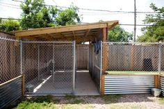 a dog kennel in the middle of a fenced off area with grass and trees