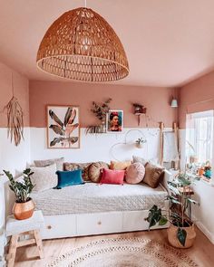 a living room with pink walls and lots of plants in the corner, including potted houseplants