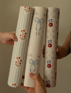 two hands holding three rolls of wrapping paper