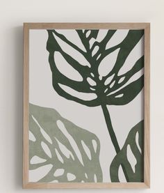 a green and white leaf print hangs on the wall next to a wooden framed object