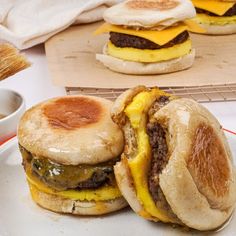 two cheeseburgers are sitting on a plate next to some dipping sauce and bread