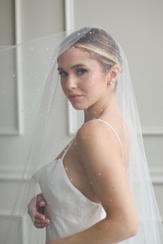 a woman wearing a wedding veil and holding her hand on her hip while looking at the camera