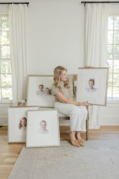 a woman sitting in a chair holding two framed pictures