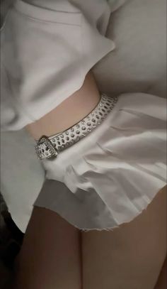 a woman wearing a white skirt with a silver belt around her waist and the bottom of her panties