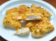 a white plate topped with cheesy hash browns and chicken breast patties on top of a wooden table