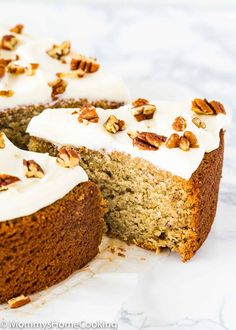 a cake with white frosting and pecans on top is cut in half to show the inside