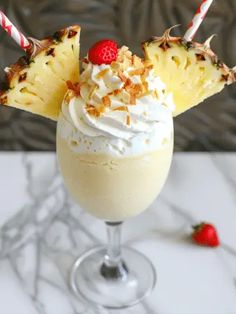 a drink with whipped cream, pineapple and strawberries