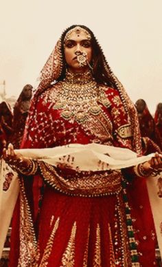 a woman dressed in red and gold standing next to other people