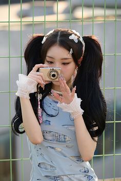 a young woman taking a photo with her camera in front of a green screen fence