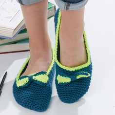 a close up of a person's feet wearing crocheted slippers and holding a pen