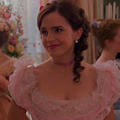 a woman in a pink dress standing next to another woman wearing a tiara and looking at the camera