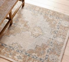 a wooden bench sitting in front of a rug on top of a hard wood floor