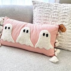 two pillows with ghost faces on them sitting on a couch