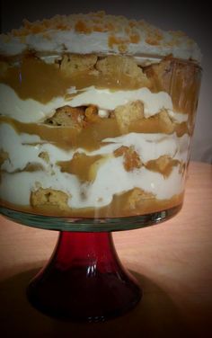 a cake with white frosting and caramel toppings on a red pedestal plate