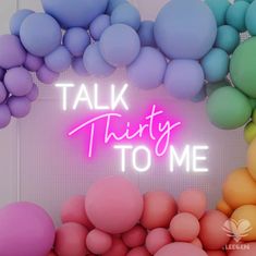 there is a neon sign that says talk thirty to me with balloons in the background