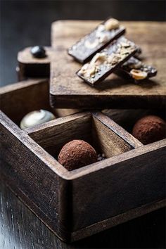 two wooden boxes filled with chocolates on top of a table